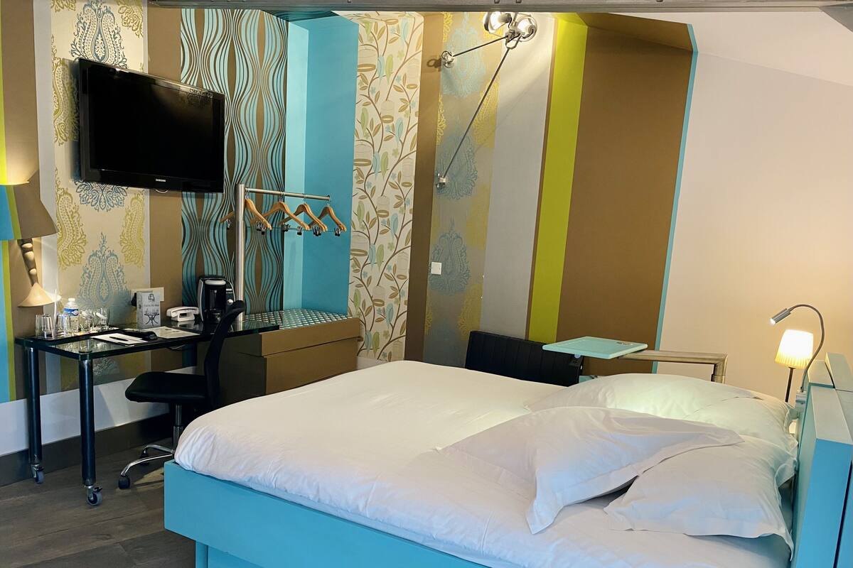 A hotel room with a bed, desk, chair, and a television.