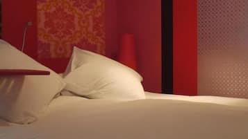 A bed with white linens in a room with red walls and a patterned wallpaper.