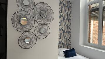 A bedroom with a bed, a window, and a wall with geometric patterned tiles.