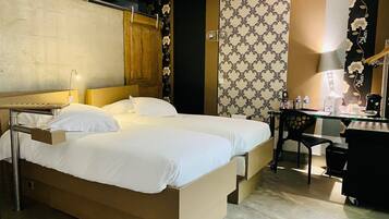A hotel room with two beds, a desk, a chair, and a wardrobe.