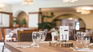 A restaurant table with numbered place settings, clear glasses, and a decorative glass jar. - Révész Hotel (Gyor)