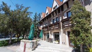 A traditional building with a balcony, stone steps, and a bench. - Révész Hotel (Gyor)
