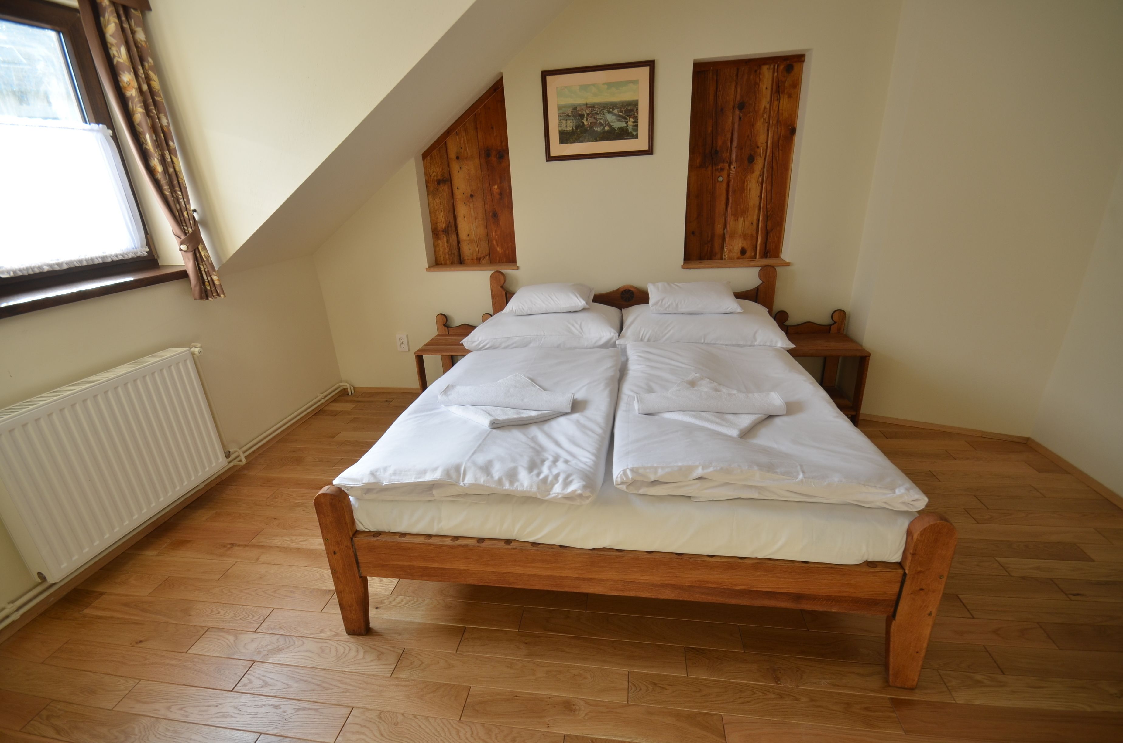 Un dormitorio con cama de madera, un radiador, una ventana con cortinas y paneles de madera en las paredes.