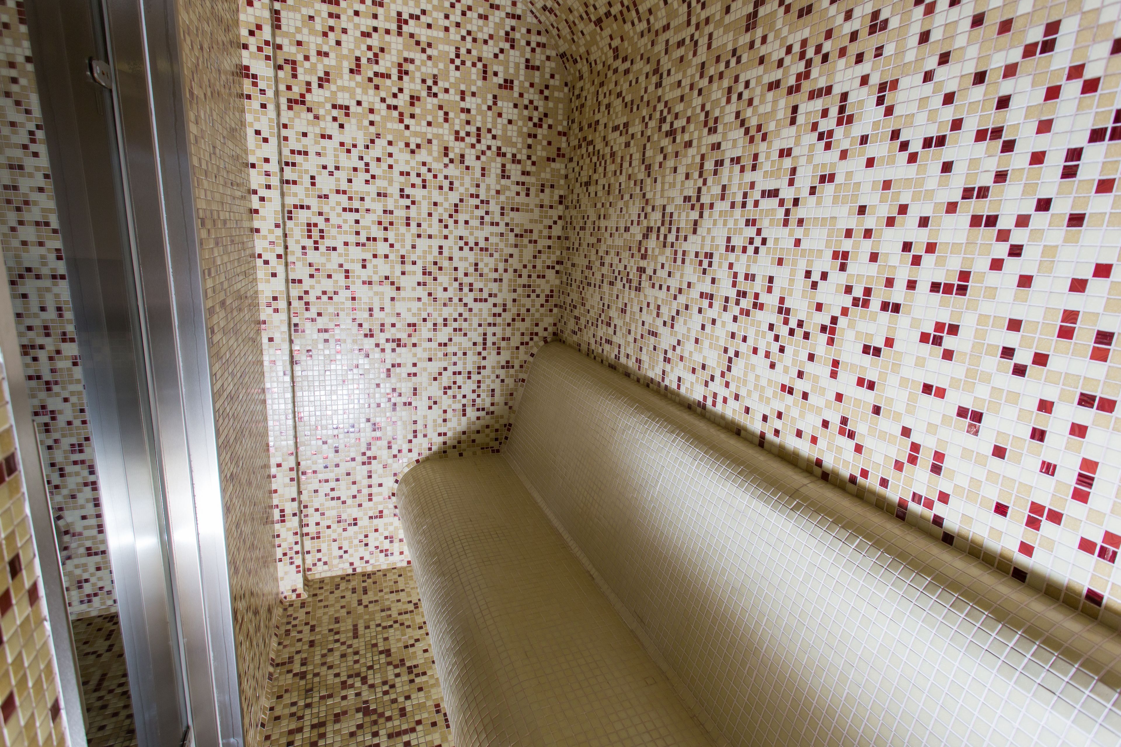 Ein Badezimmer mit Wandfliesen im Mosaik-Stil und einer Sitzbank.