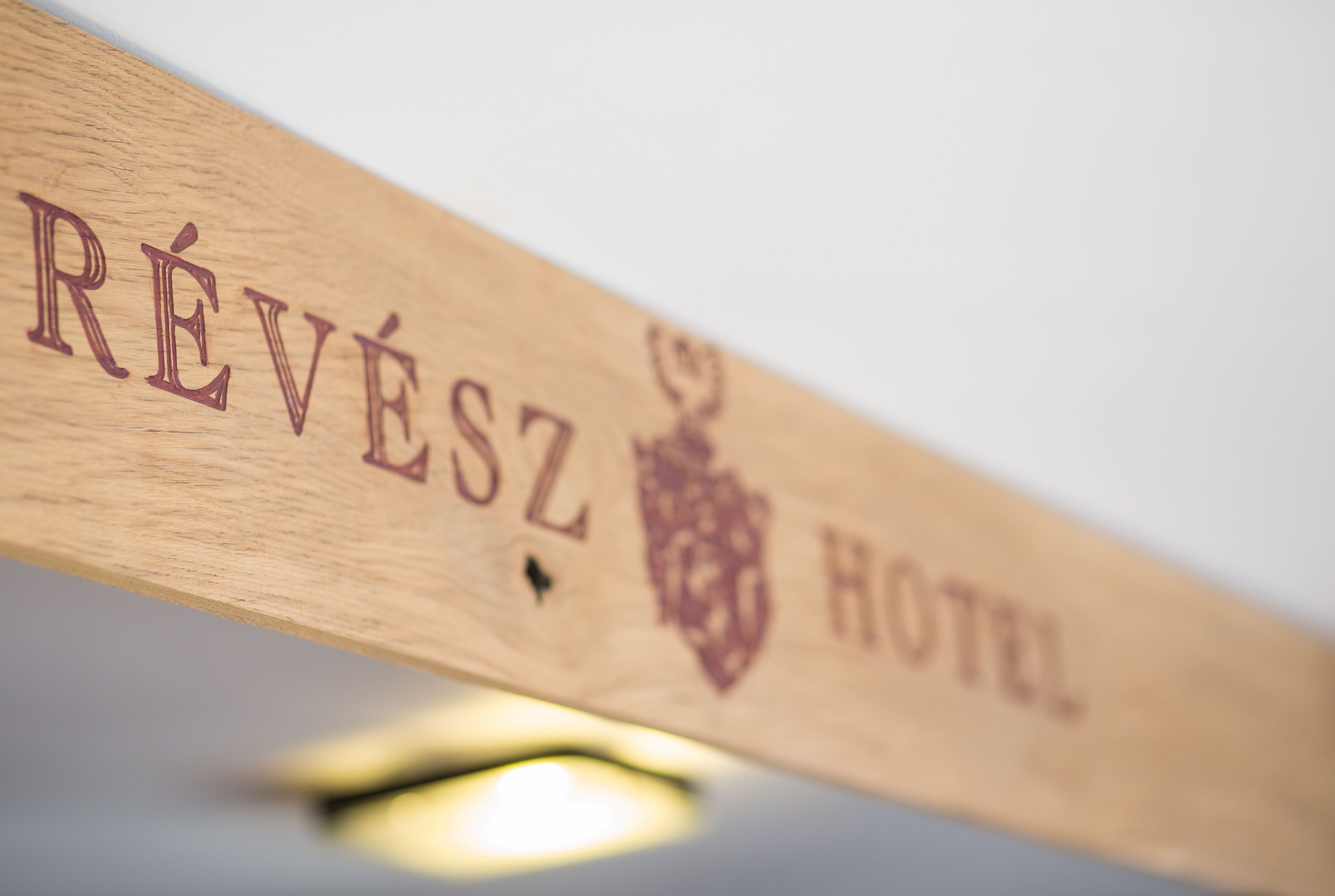 A wooden sign with the text "RÉVÉS HOTEL" and a crest emblem.