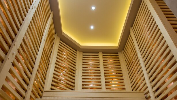 A wooden staircase with a geometric ceiling design and recessed lighting. - Révész Hotel (Gyor)