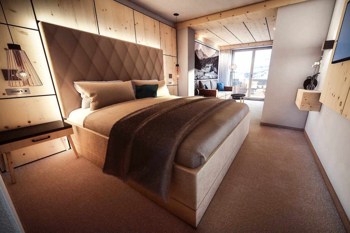 Un dormitorio con una cama grande, cabecera de madera y vistas a las montañas a través de una ventana.