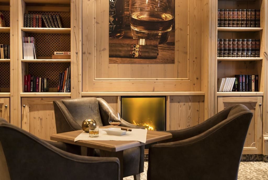 A library with bookshelves, a fireplace, and a table with chairs.