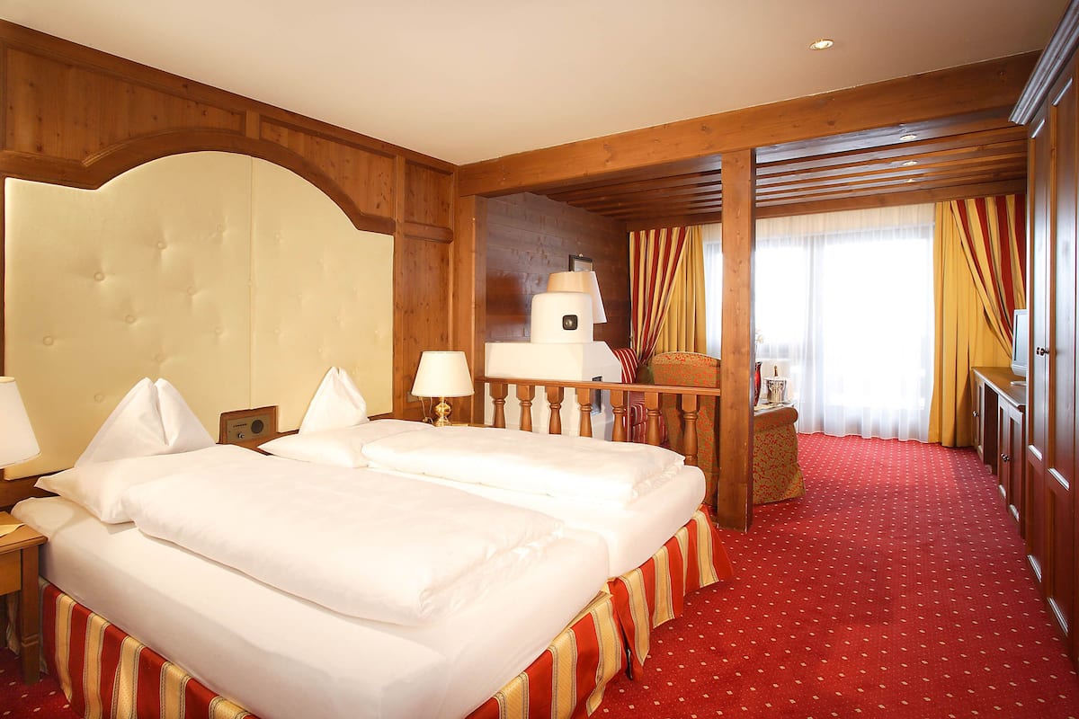 Habitación de hotel con dos camas, paneles de madera, alfombra roja y vistas al exterior.