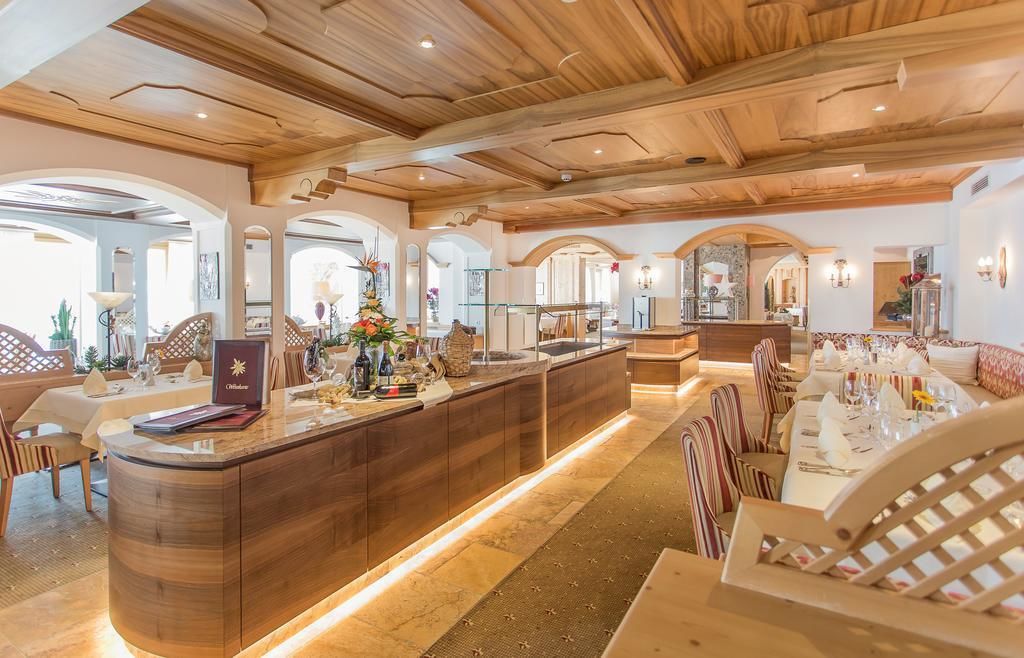 Een ruime hotellobby met een houten receptiebalie, comfortabele zitplaatsen en uitzicht op de aangrenzende eetruimte.