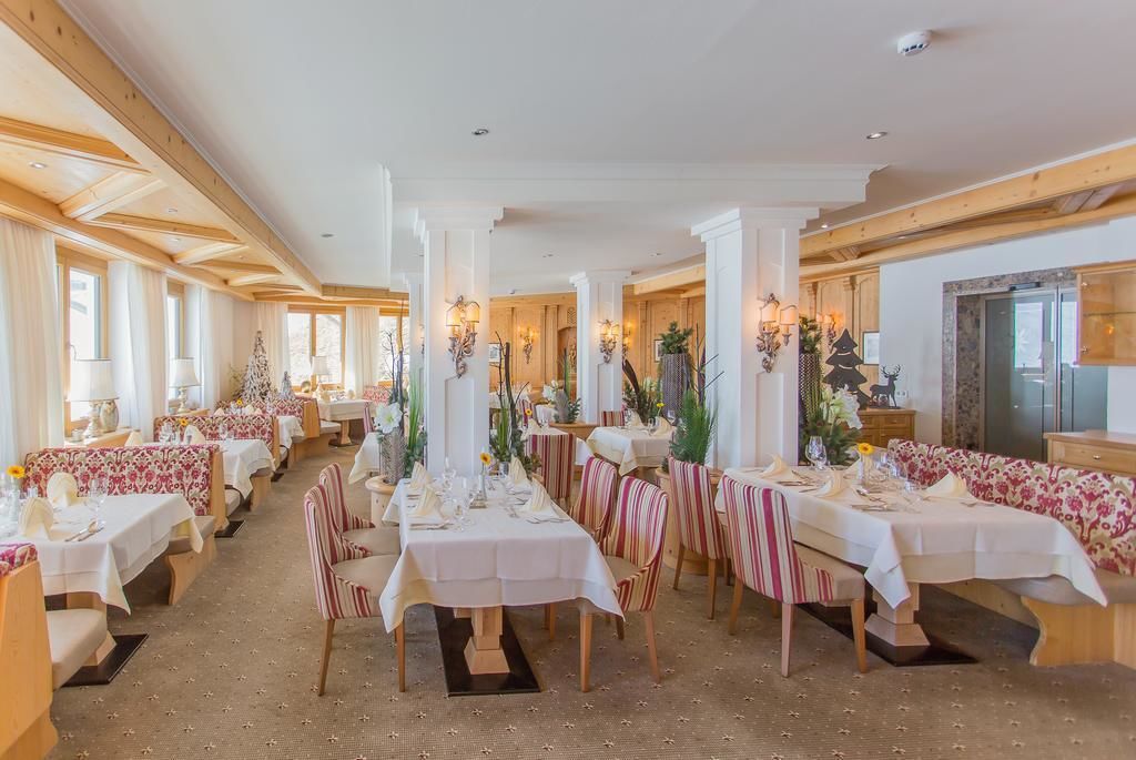 Un restaurante con varias mesas y cabinas, cada una con manteles blancos y sillas a rayas.