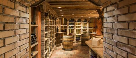 A wine cellar with brick walls, wooden shelves, and barrels.