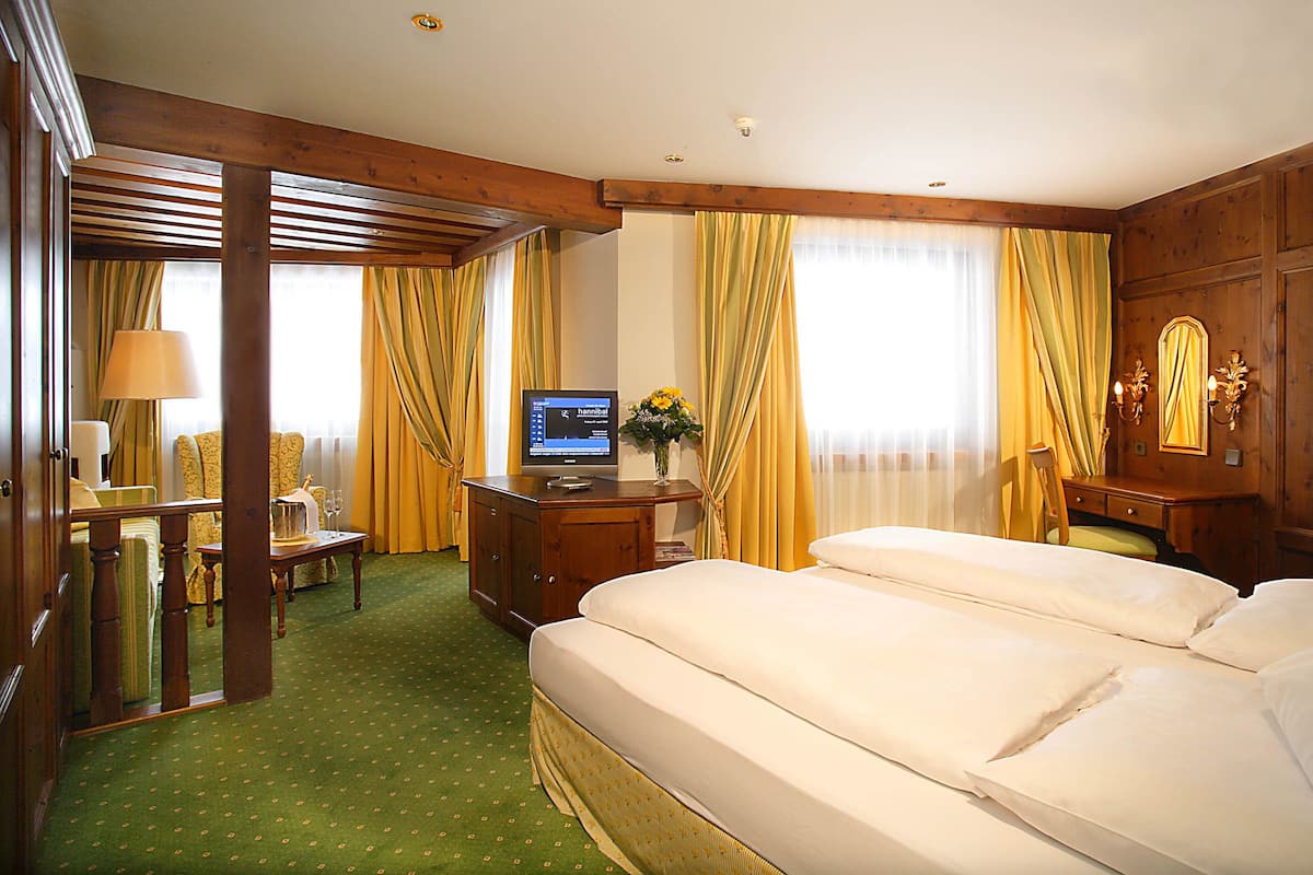 Habitación de hotel con una cama, un escritorio con computadora, una silla y una lámpara.