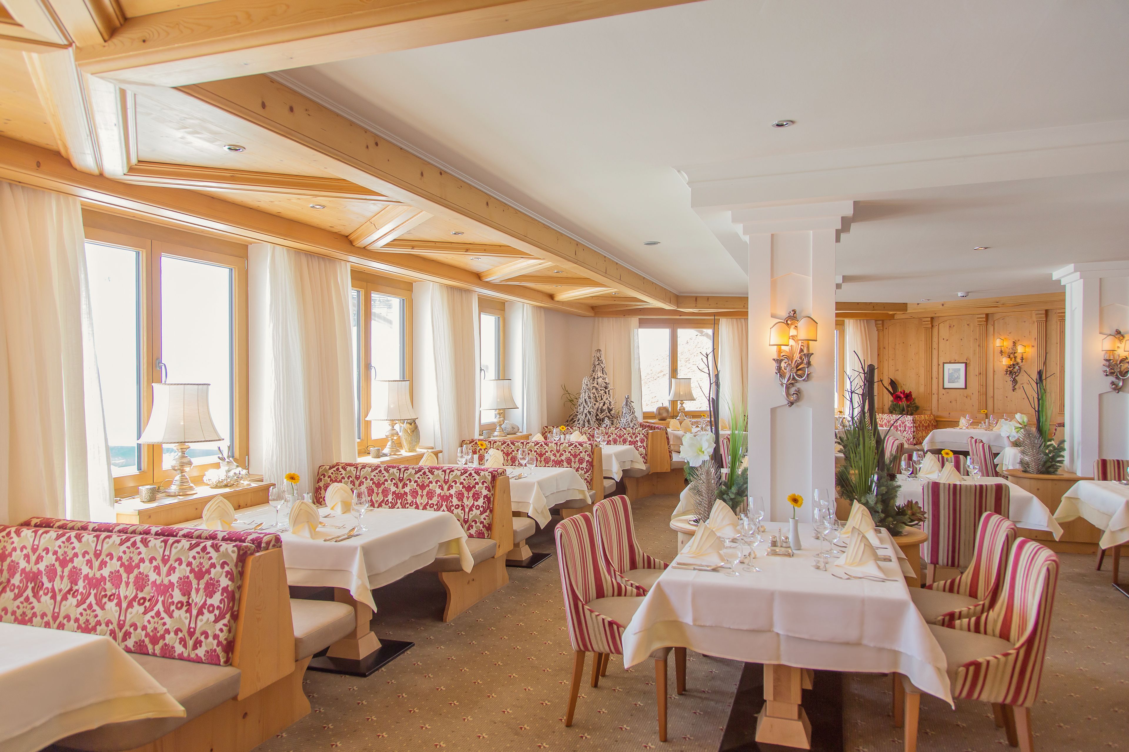 A restaurant with wooden beams, large windows, and tables set for dining.