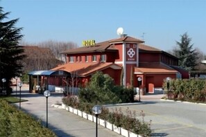 A red building with a 'HOTEL' sign, a satellite dish, and a covered area with tables and chairs.