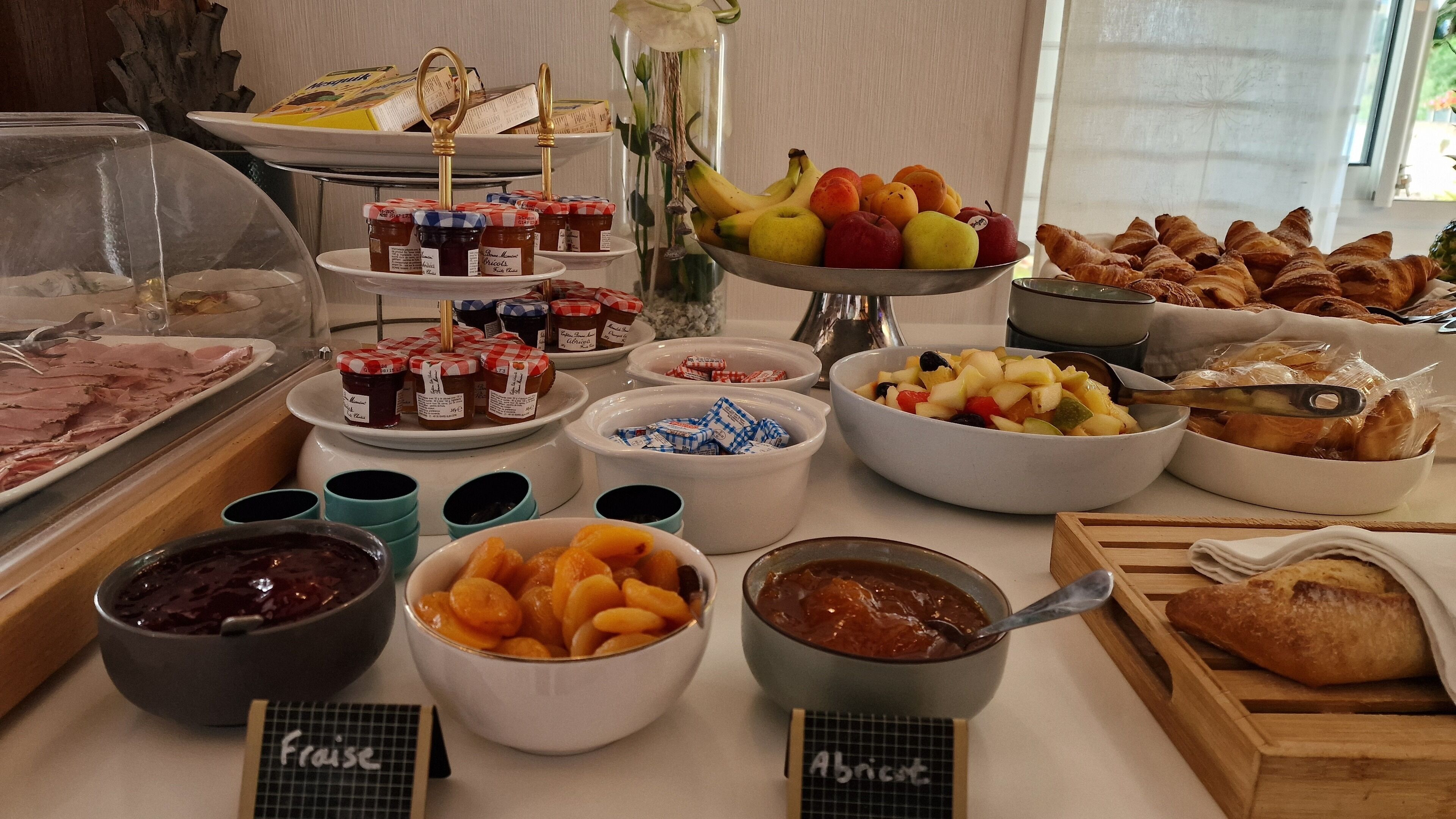 A buffet with various food items including fruits, pastries, and condiments.