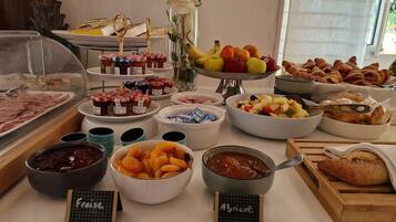A buffet with various food items including fruits, pastries, and condiments.