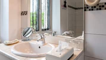 Un baño moderno con un lavamanos grande blanco, un espejo y una ventana con persianas verticales.