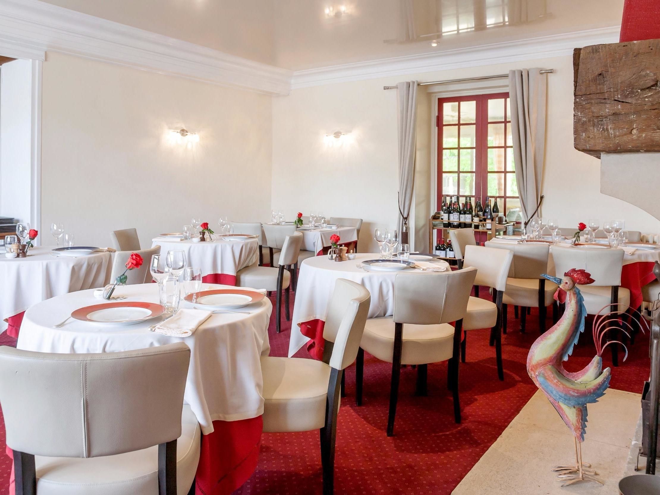Ein Restaurant mit runden Tischen, weißen Tischdecken und roten Akzenten.