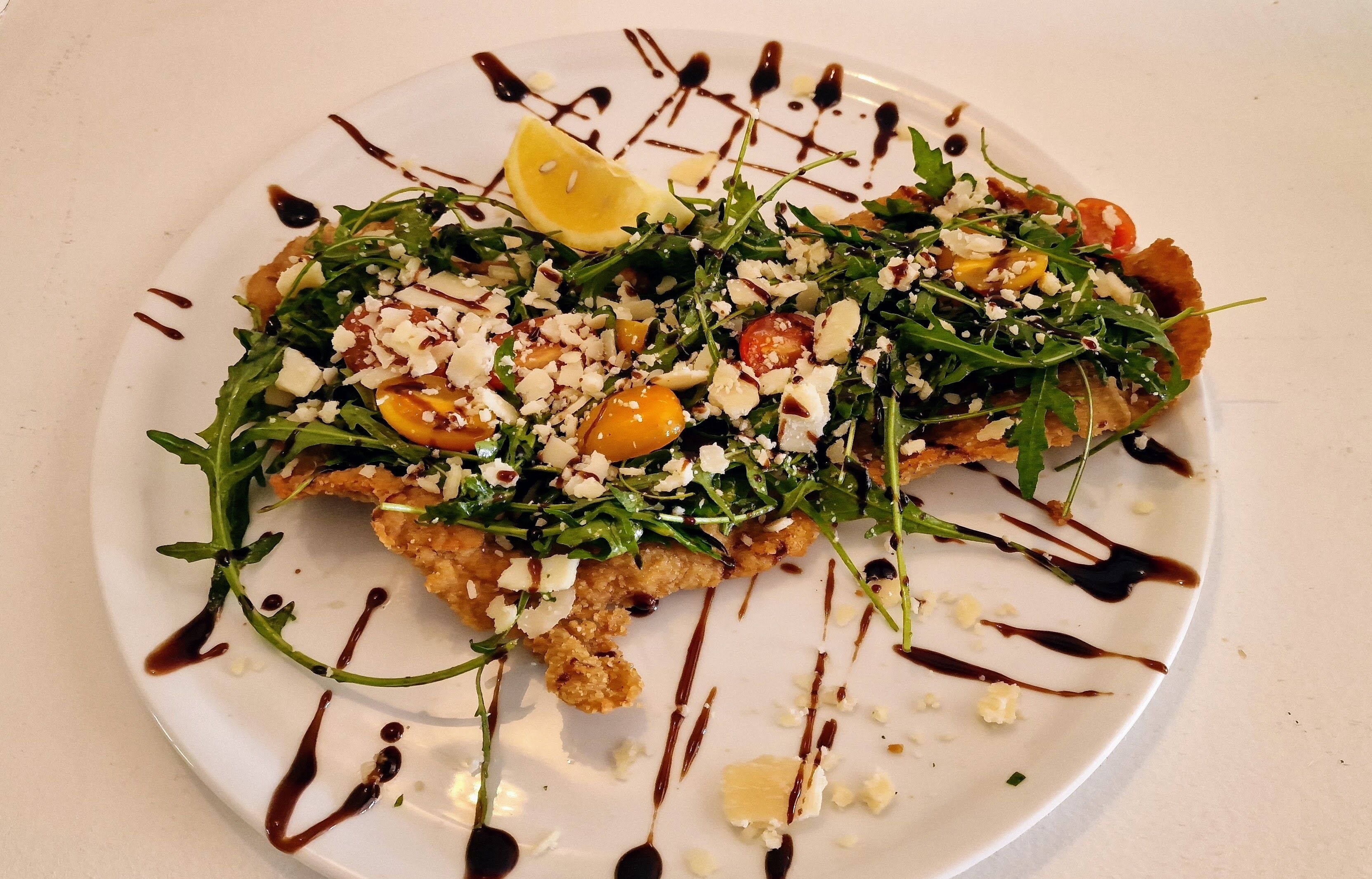 A plate of food with a lemon wedge and a drizzle of sauce.