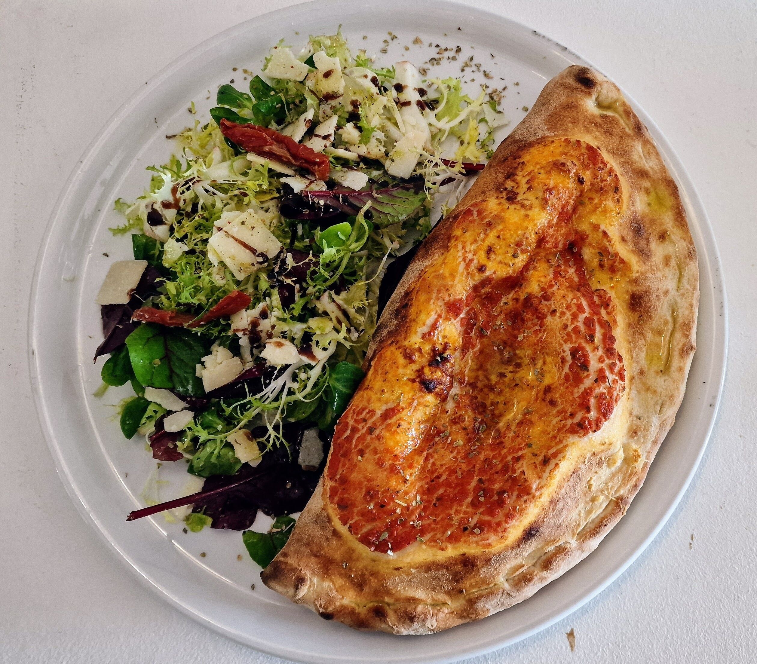 A plate with a grilled cheese sandwich and a mixed green salad.