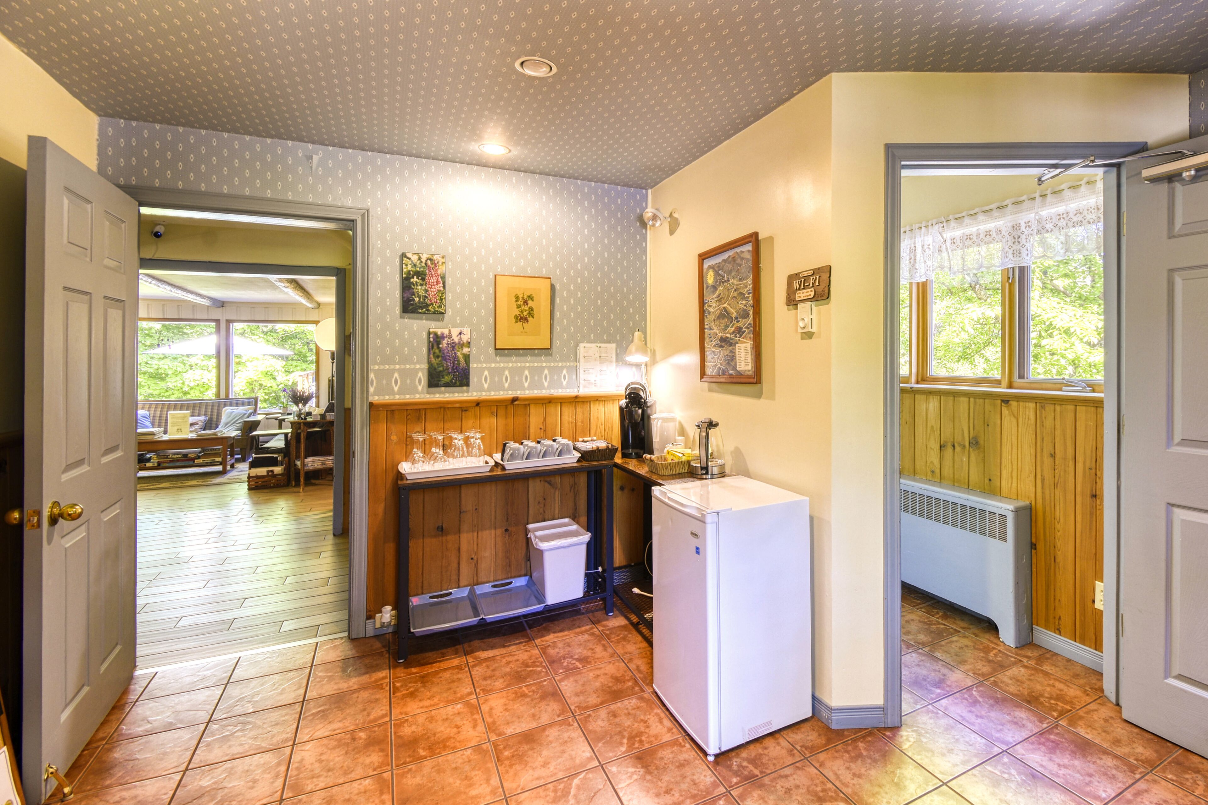 A kitchen with a refrigerator, a sink, and a window with a view of greenery.