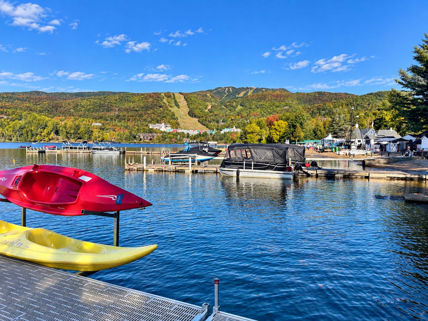 A lakeside dock with boats, a red kayak, and a yellow kayak.