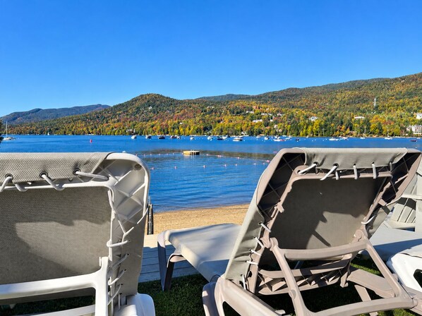 Outdoor lounge chairs facing a lake with boats, surrounded by hills and autumn foliage. - Auberge Le Lupin-Self Check-in (Mont-Tremblant)