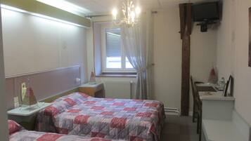A hotel room with two beds, a desk, a chair, a television, and a window with curtains.