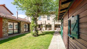 A courtyard with a stone building, wooden walls, and a tree. - Hôtel-Restaurant La Crèche et sa piscine intérieure - Logis Hôtels (La Chomette)