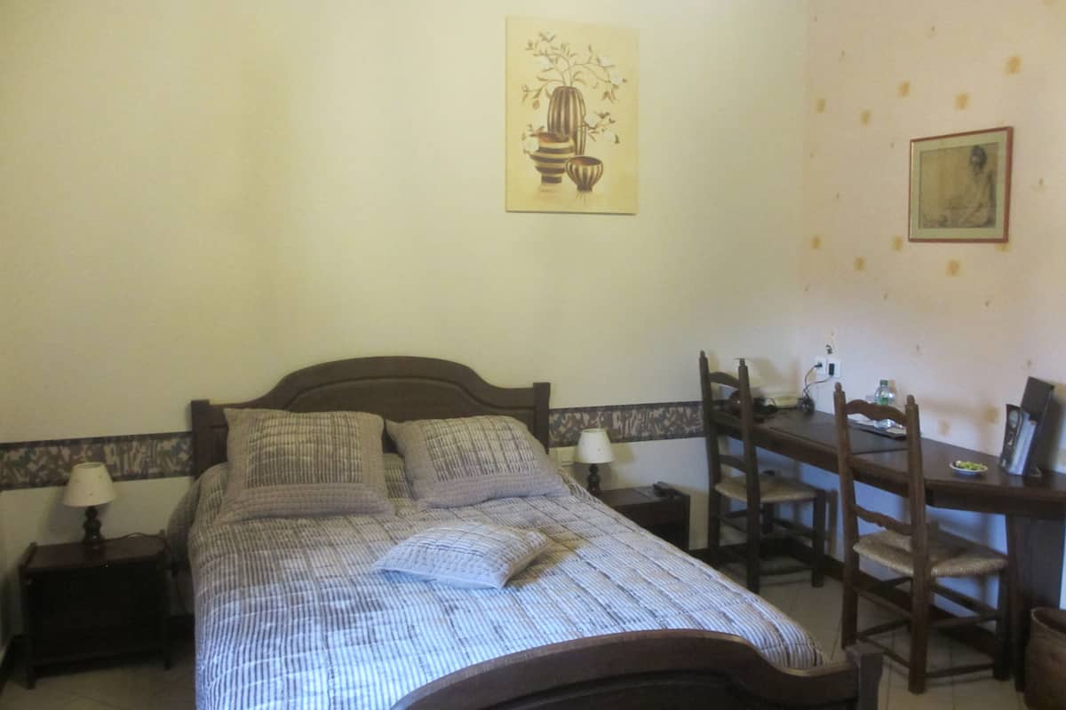 A bedroom with a bed, bedside tables, a desk, and chairs.