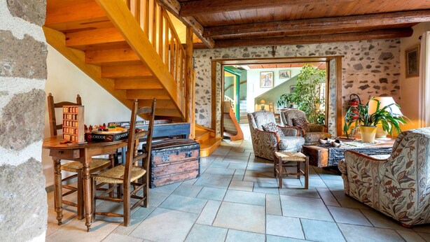 A cozy living room with a wooden staircase, stone walls, and a view of the outside. - Hôtel-Restaurant La Crèche et sa piscine intérieure - Logis Hôtels (La Chomette)