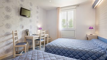 Une chambre avec deux lits, un bureau, des chaises, une télévision et une fenêtre avec des rideaux.