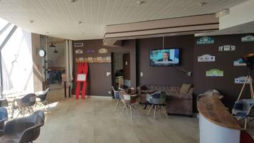 Un área de recepción con televisión, asientos y una silla roja.