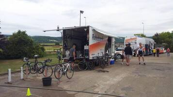 A truck with 'Rabobank' branding parked at a campsite with bicycles and people around.