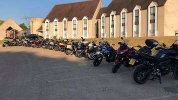 A row of motorcycles parked in front of a building with a brown roof and white windows.