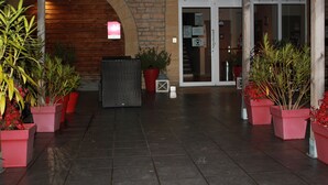 Una entrada de edificio con fachada de ladrillo, arco de madera y plantas en macetas.