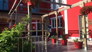 Un edificio rojo con balcón de madera, plantas en macetas y un letrero de restaurante.
