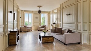 Un salon spacieux avec un grand canapé, deux fauteuils, une table basse et une cheminée.