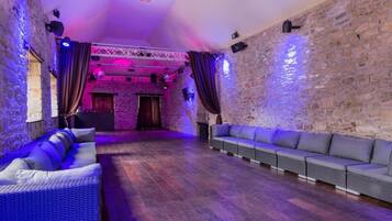 A room with stone walls, a wooden floor, and a stage area with curtains.