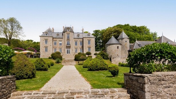 Un grand bâtiment en pierre doté d’une entrée centrale et d’une tour.