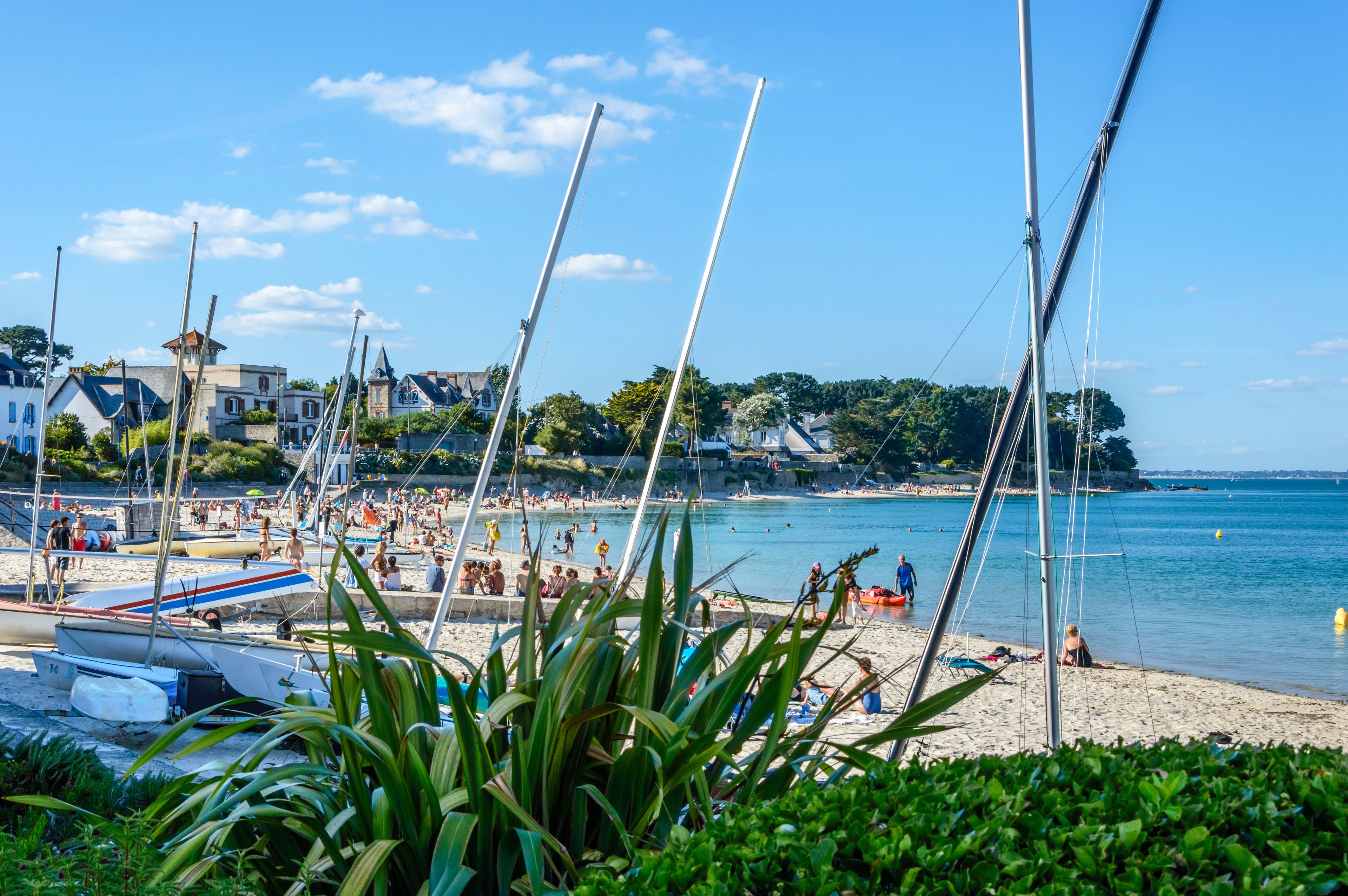 A beach with boats, people, and buildings in the background.