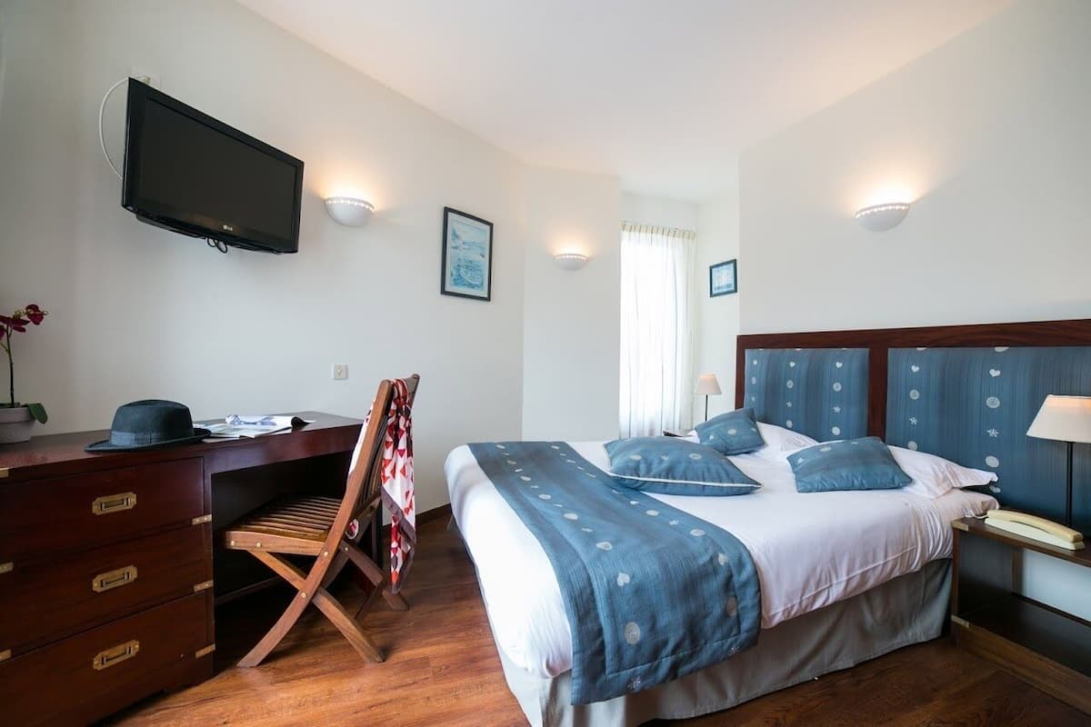 Un dormitorio con una cama, un escritorio, un televisor y una silla.
