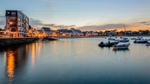 Een hotel aan het water met meerdere balkons, een jachthaven met boten en een rustige avond.