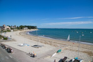 Une plage avec des bateaux, un ciel dégagé et des bâtiments en arrière-plan.