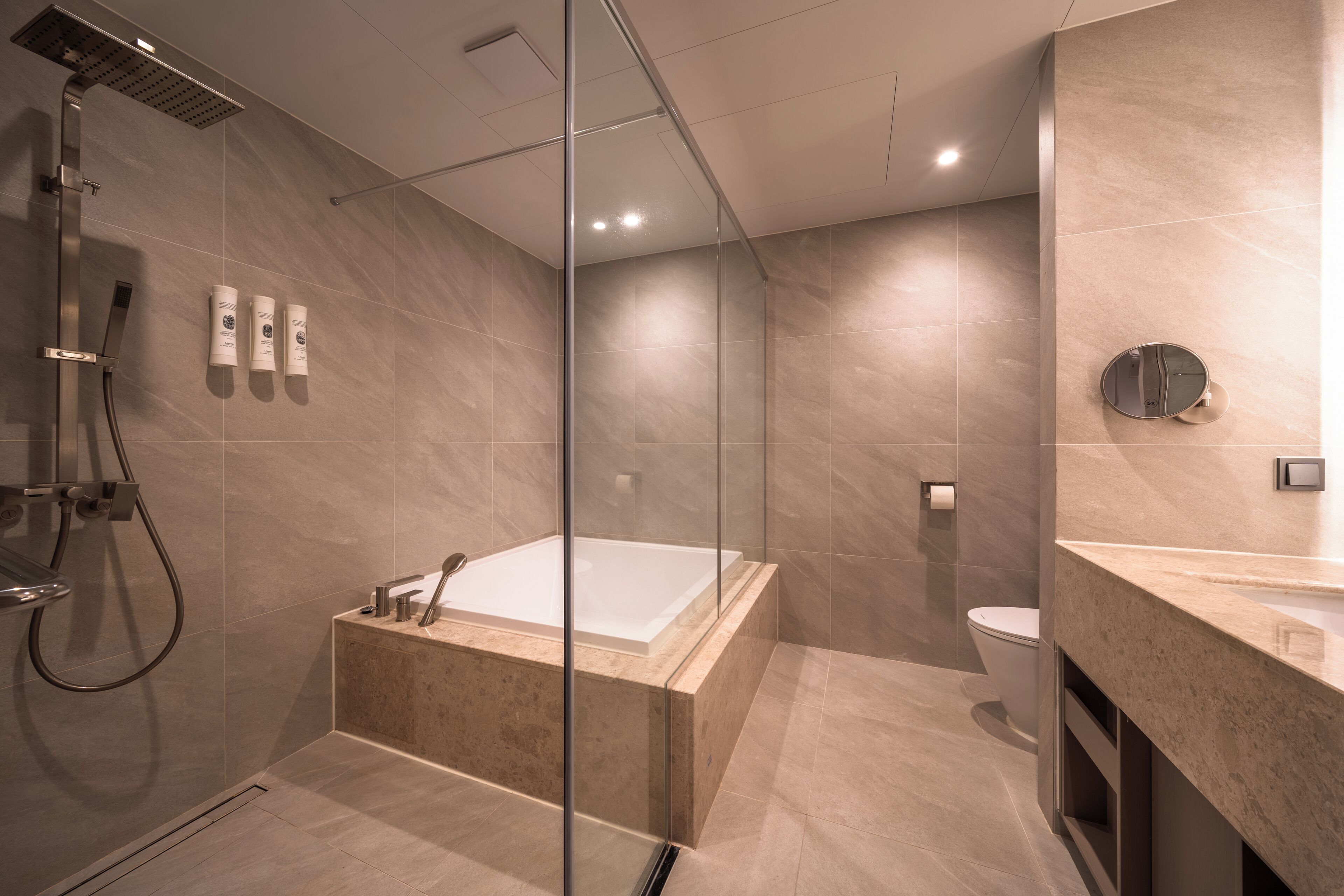 A modern bathroom with a glass-enclosed shower, a freestanding bathtub, and a toilet.