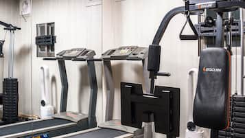 Uma academia com esteiras, um banco de musculação e diversos aparelhos de exercícios.