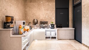 Una cocina moderna de hotel con paredes de mármol, una estación de café y una puerta para personal exclusivo.