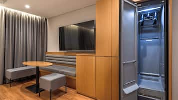 A compact living space with a sofa, a small table, a bench, and a built-in refrigerator.
