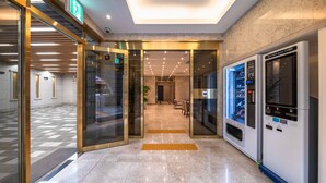En moderne lobby med et check-in/check-out system, en glas elevator og en selvbetjenings kiosk.